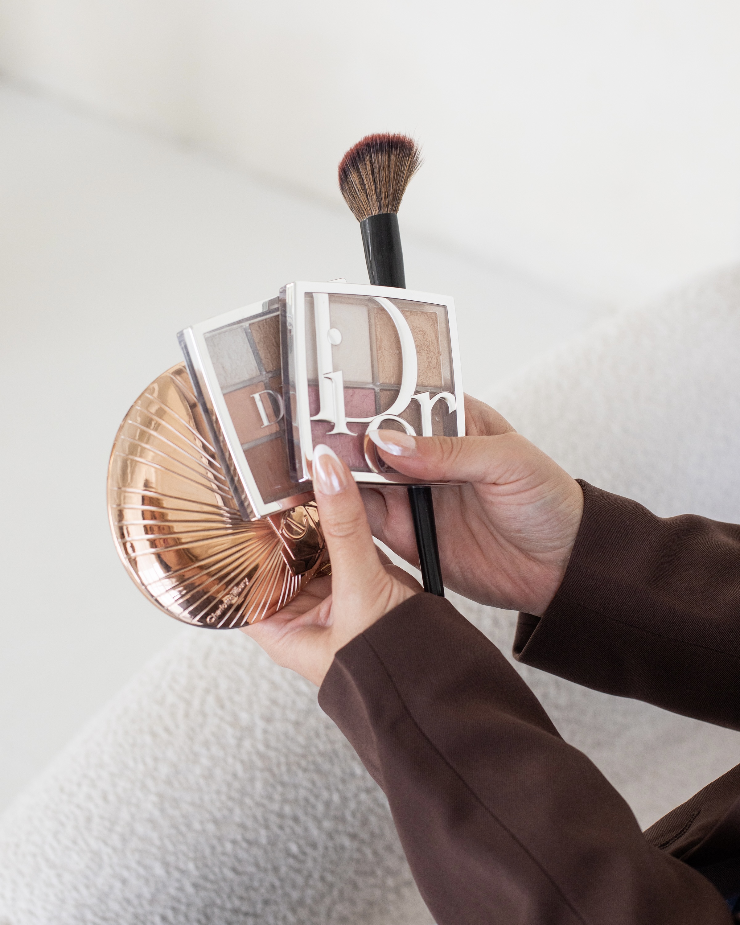 A makeup brush and compact held over a palette, close up.