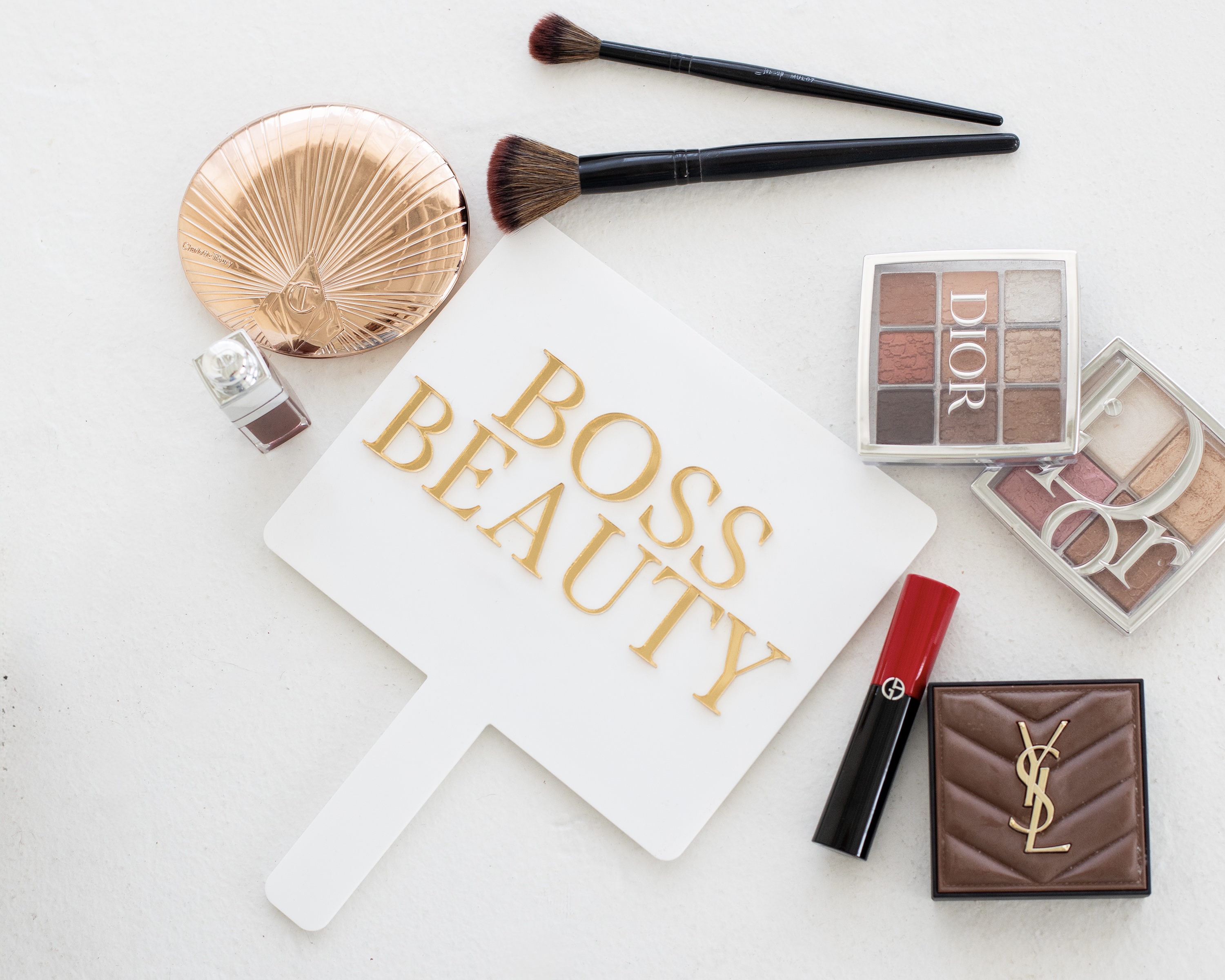 Flat lay of makeup brushes, palettes, and luxury beauty products.