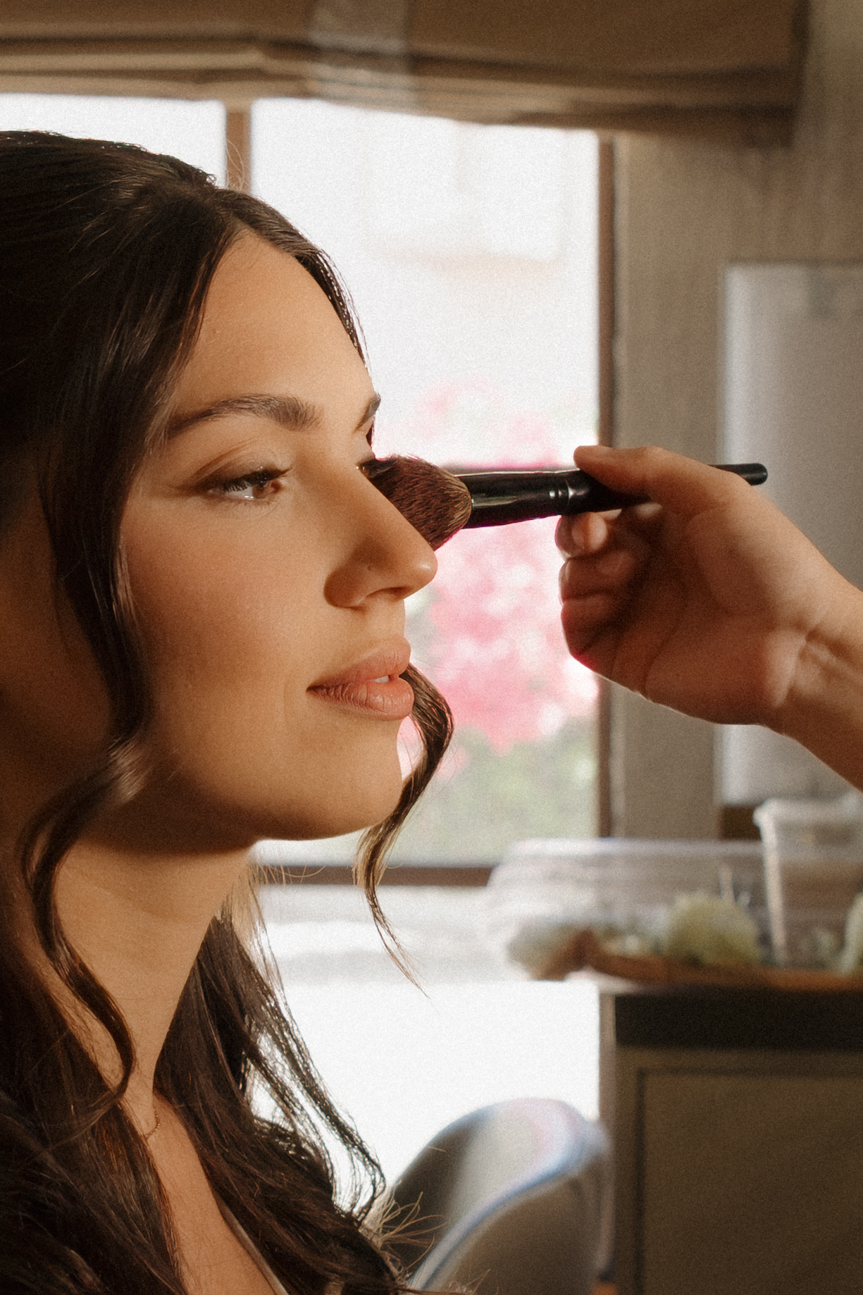 Makeup artist applying finishing touches during bridal preparation.
